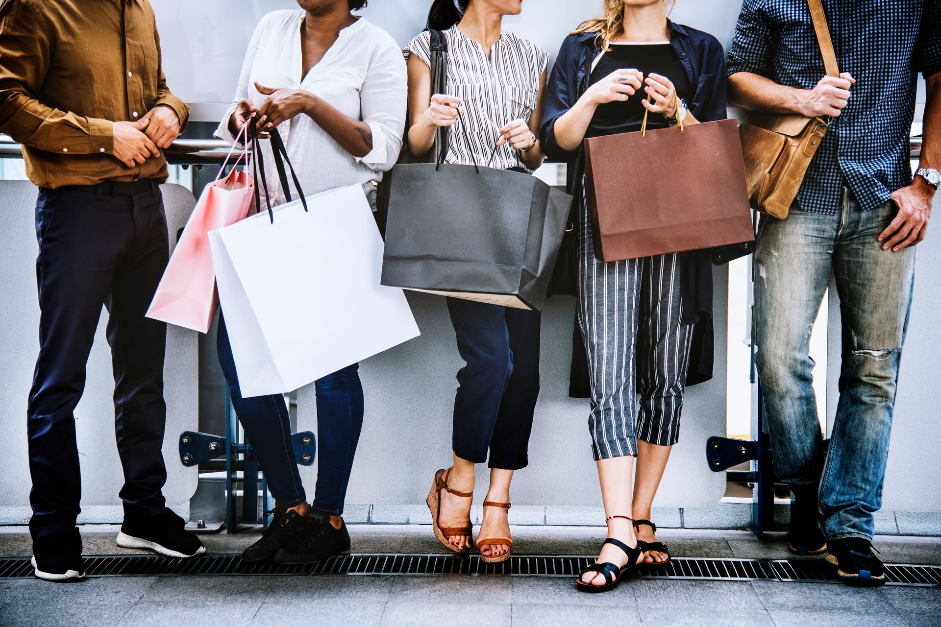 A group of people standing next to each other holding shopping bags.