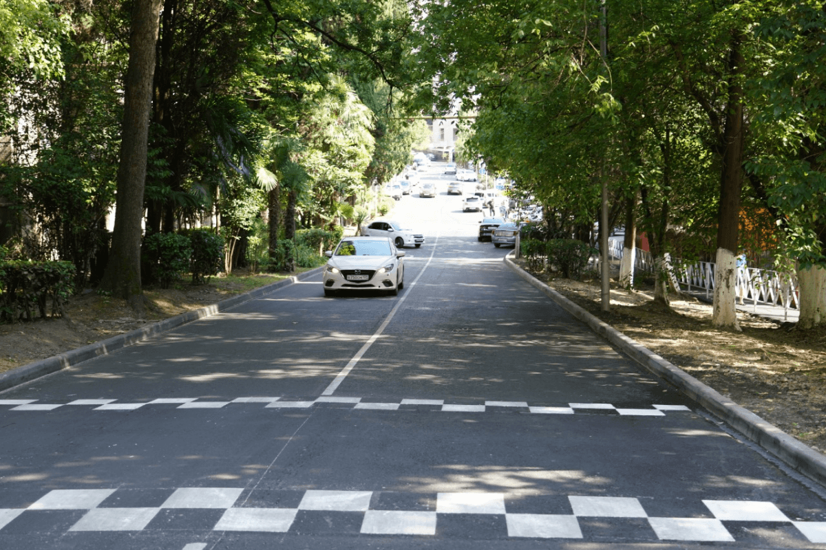 Tree-lined street with cars driving uphill on a quiet road