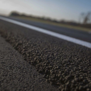 Low-angle view of a paved road with a white lane line and blurred horizon