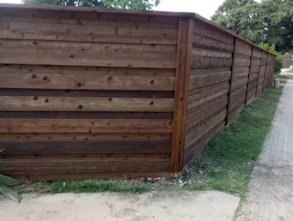 A wooden fence is sitting on the side of a road.