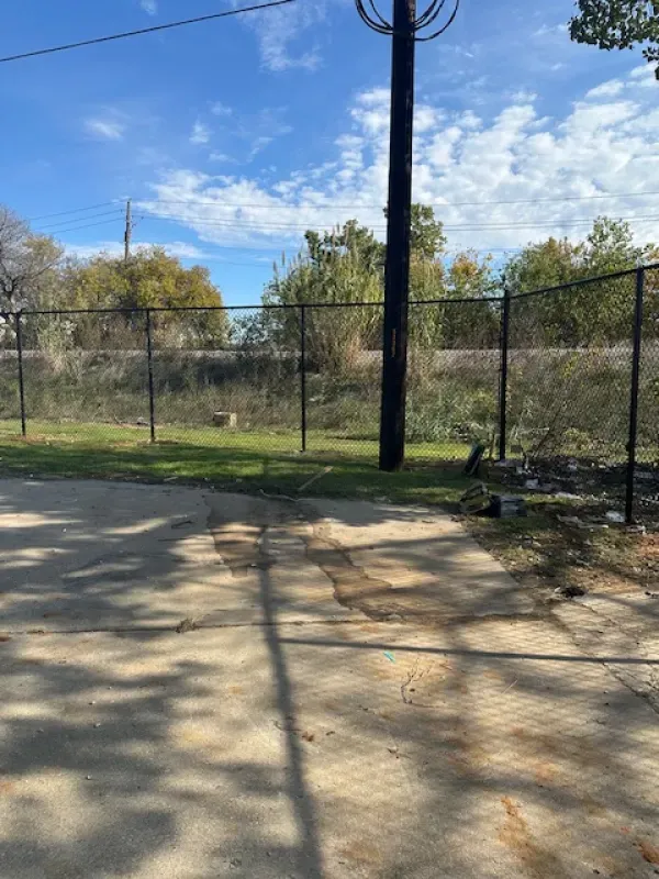 A chain link fence is surrounding a concrete driveway.