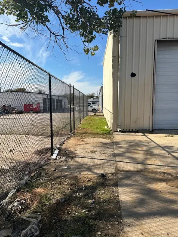 A chain link fence surrounds a building with a white garage door.