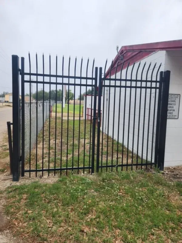 A black wrought iron gate is sitting in front of a white building.