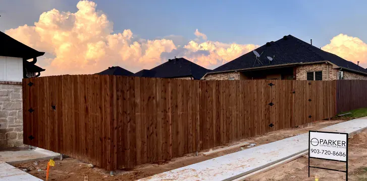 A wooden fence is surrounded by houses in a residential area.