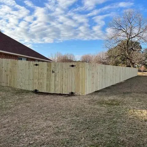 A wooden fence with a gate in the backyard of a house.