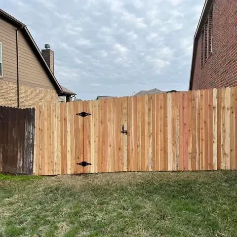 A wooden fence with a gate in the backyard of a house.