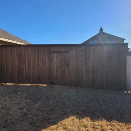 A wooden fence surrounds a shed in a backyard.