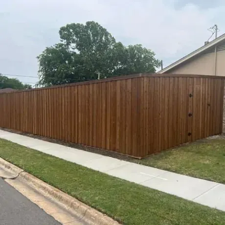 A wooden fence along a sidewalk next to a house.