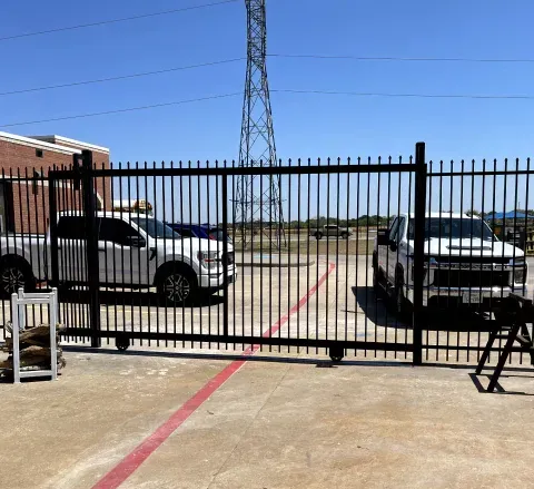 A fence with cars parked behind it and a power tower in the background