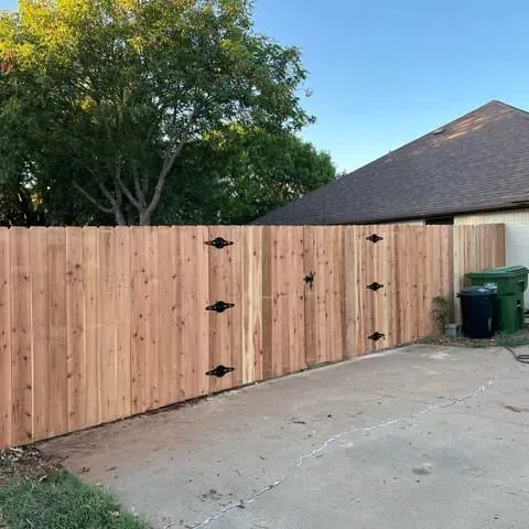 A wooden fence with a gate in front of a house.
