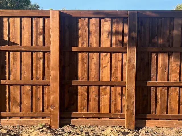A wooden fence is sitting on top of a dirt field.