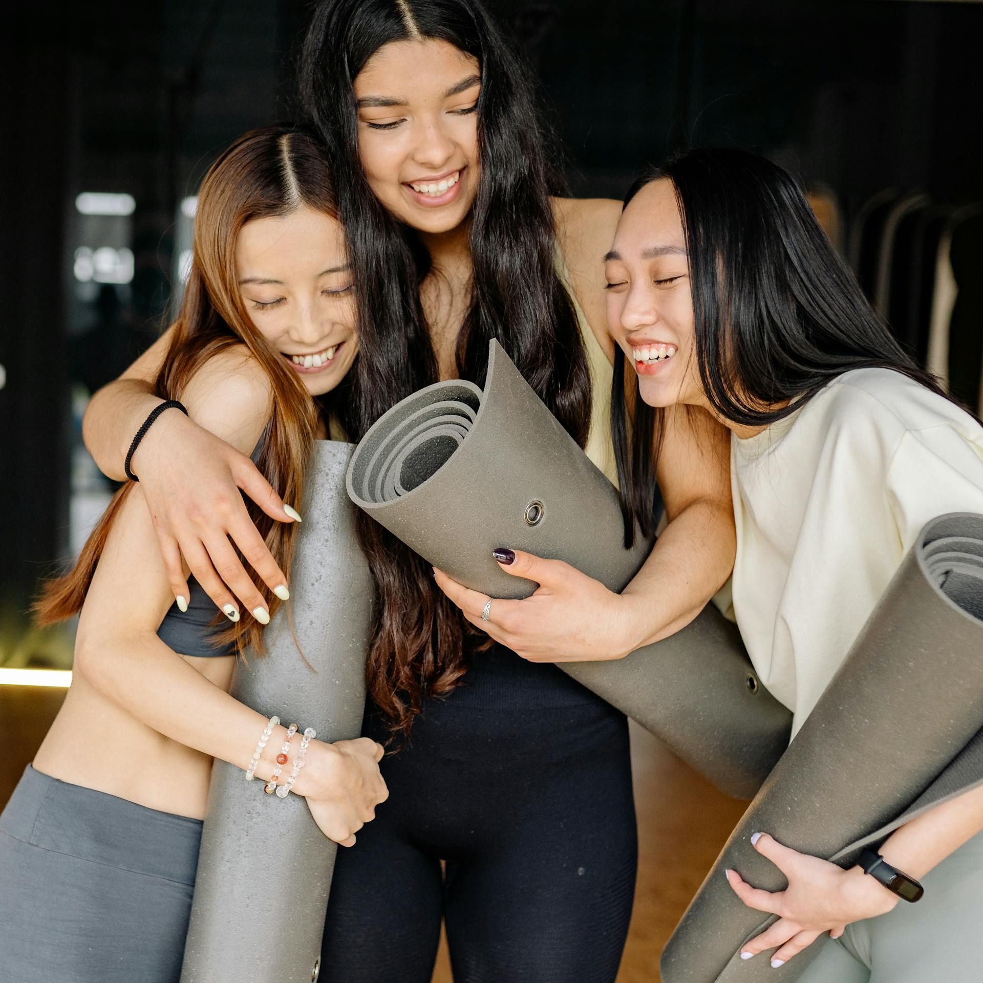 three women holding yoga mats.