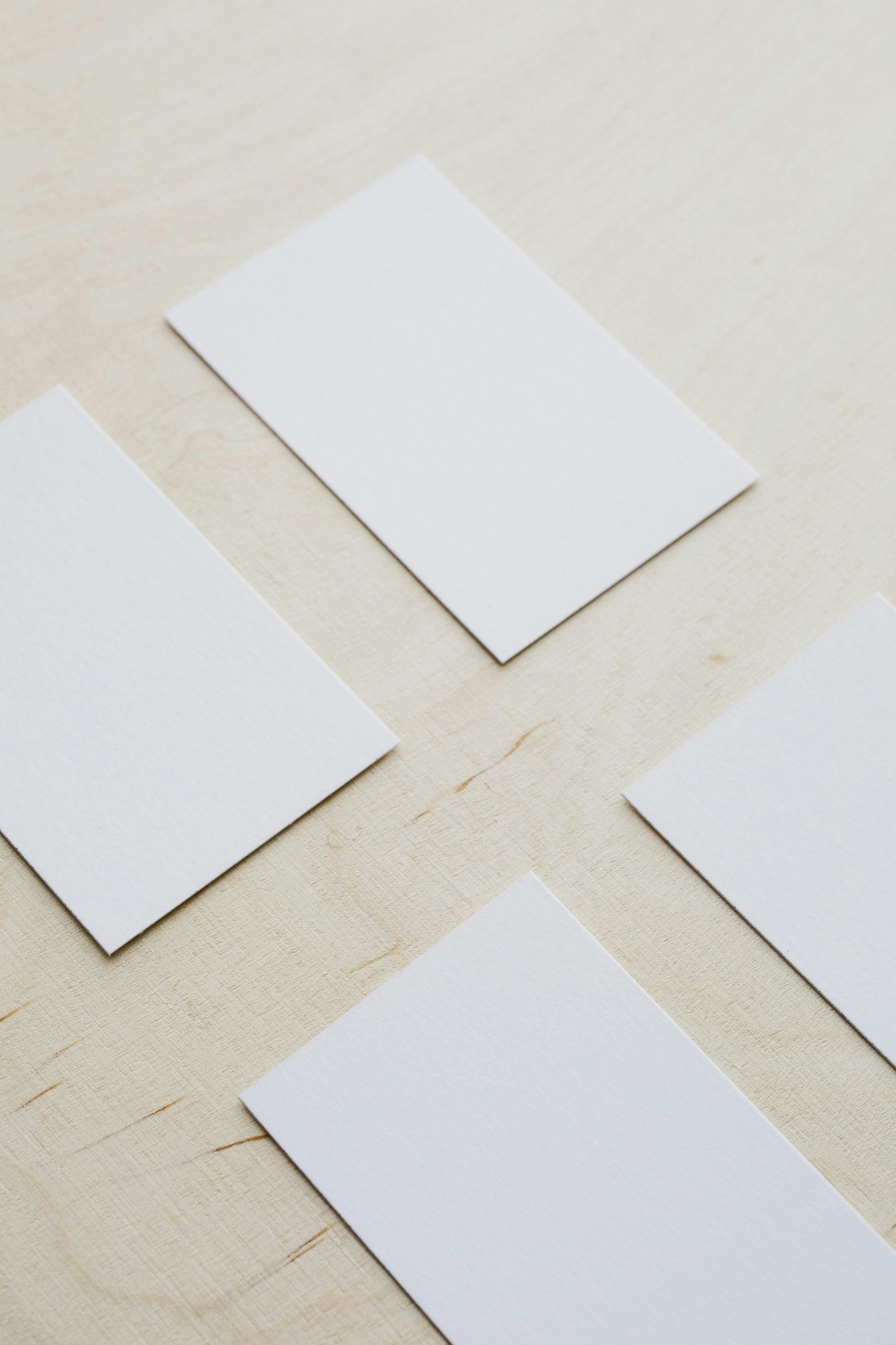 Four white business cards are stacked on top of each other on a table.