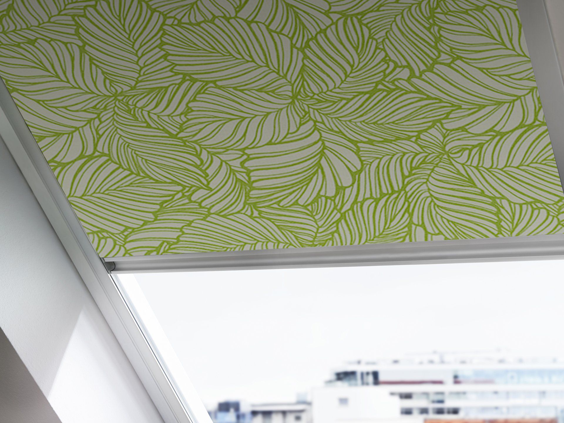 Nahaufnahme von Rollo mit grünem Blattmuster in einem Fenster in Dachschräge