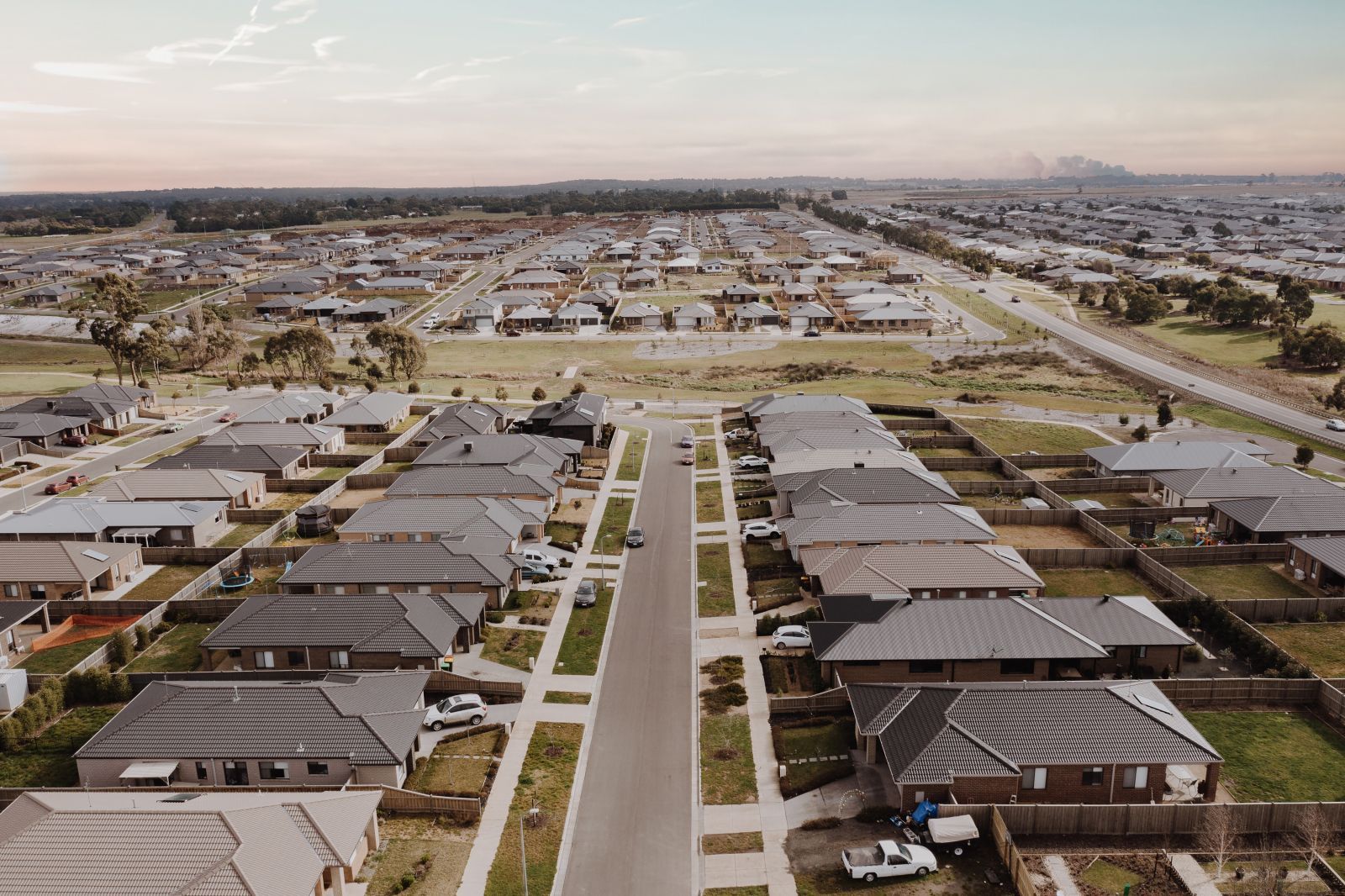 Aerial view of a suburban neighborhood with rows of modern houses and straight streets under a clear sky