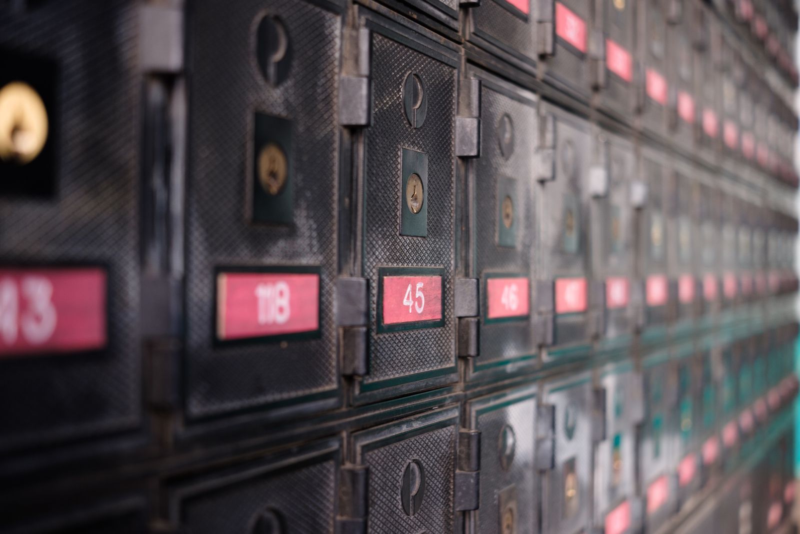Rows of dark mailboxes with pink number labels in a narrow corridor