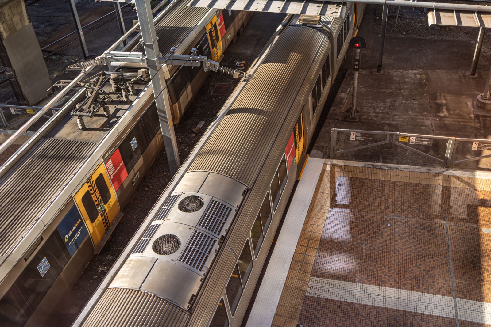 Overhead view of a train station platform with a silver train on the tracks and wet floor reflections
