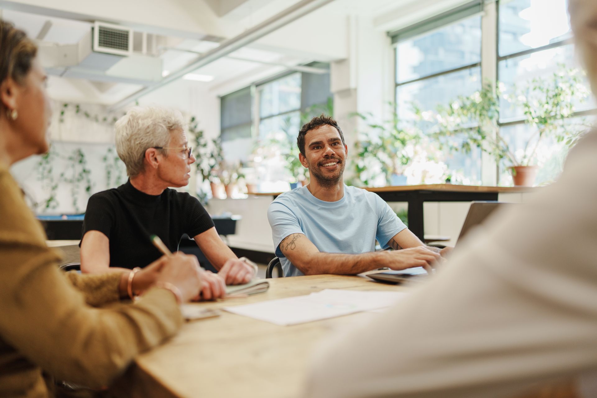 People seated around a table in a bright meeting room, smiling and talking.