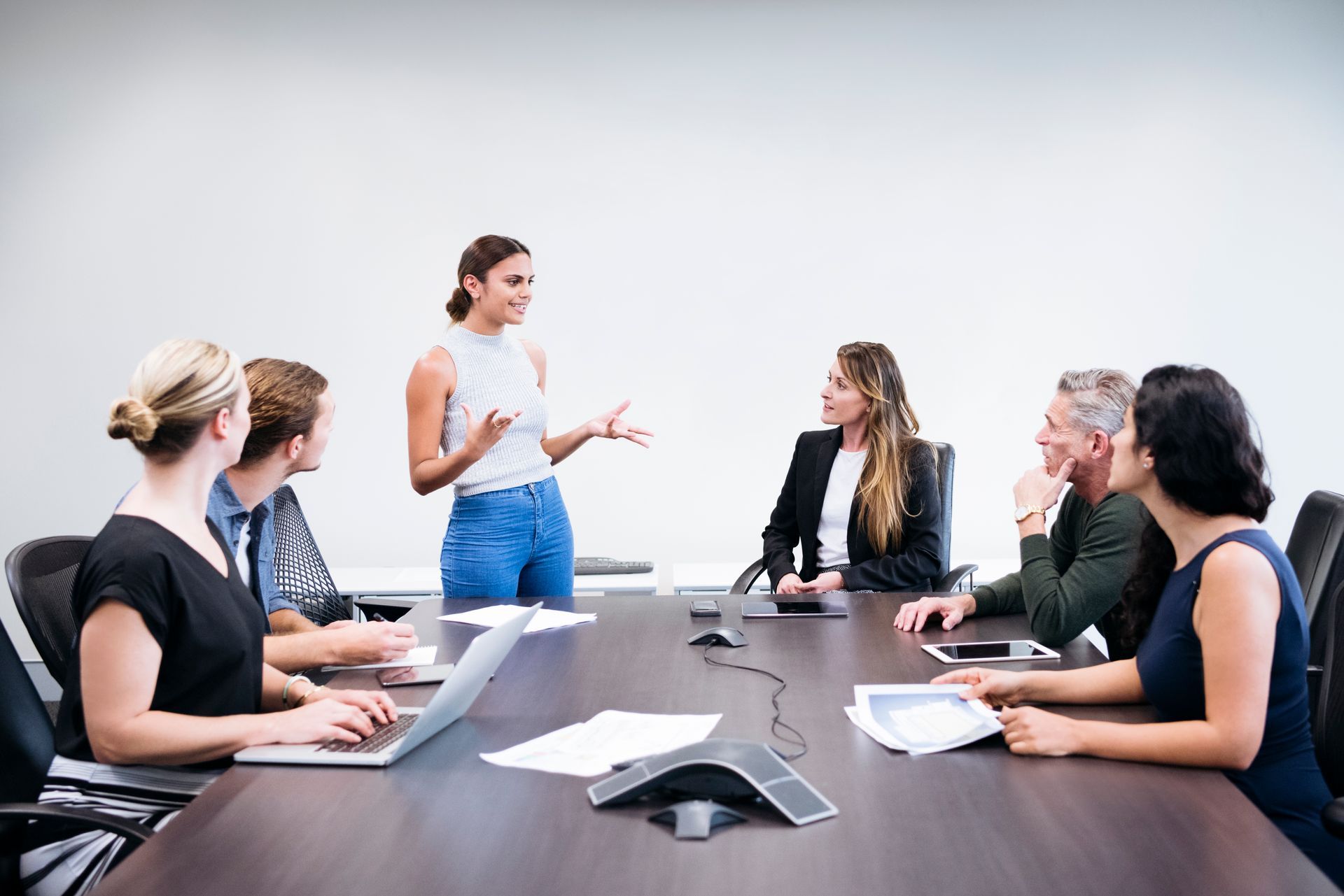 Teacher leading a discussion with students in a bright classroom around a table