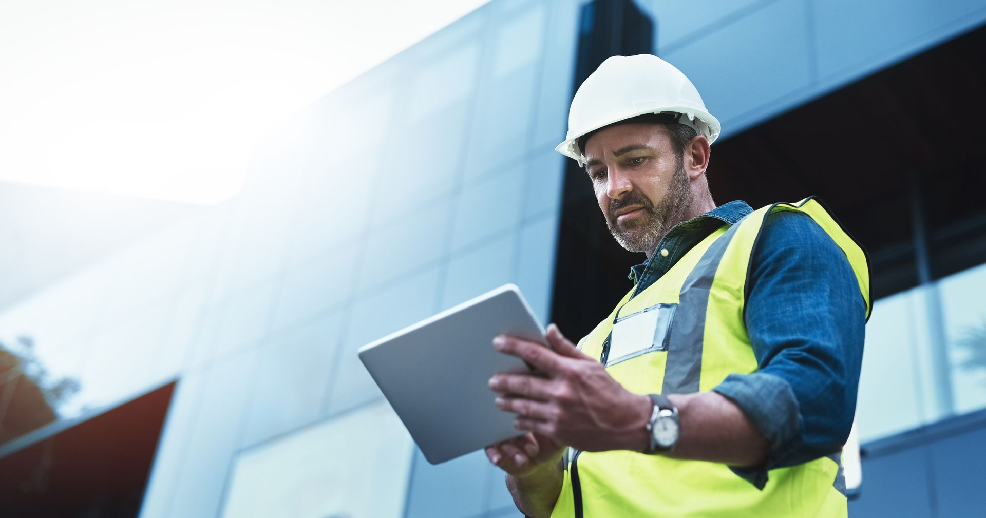 Construction manager reviewing plans on tablet at modern commercial building site. Construction manager reviewing plans on tablet at modern commercial building site.
