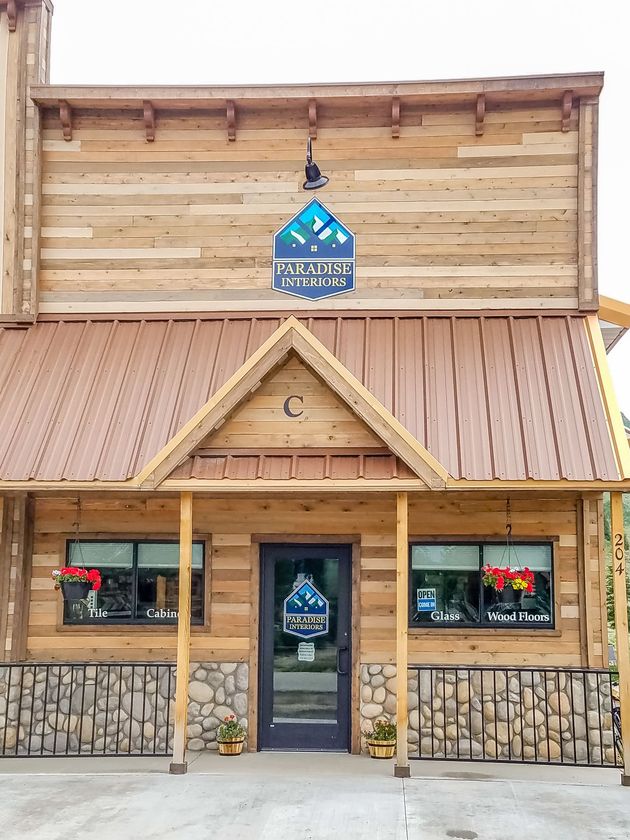 Wooden building with a brown metal roof, stone accents, and a sign that reads 