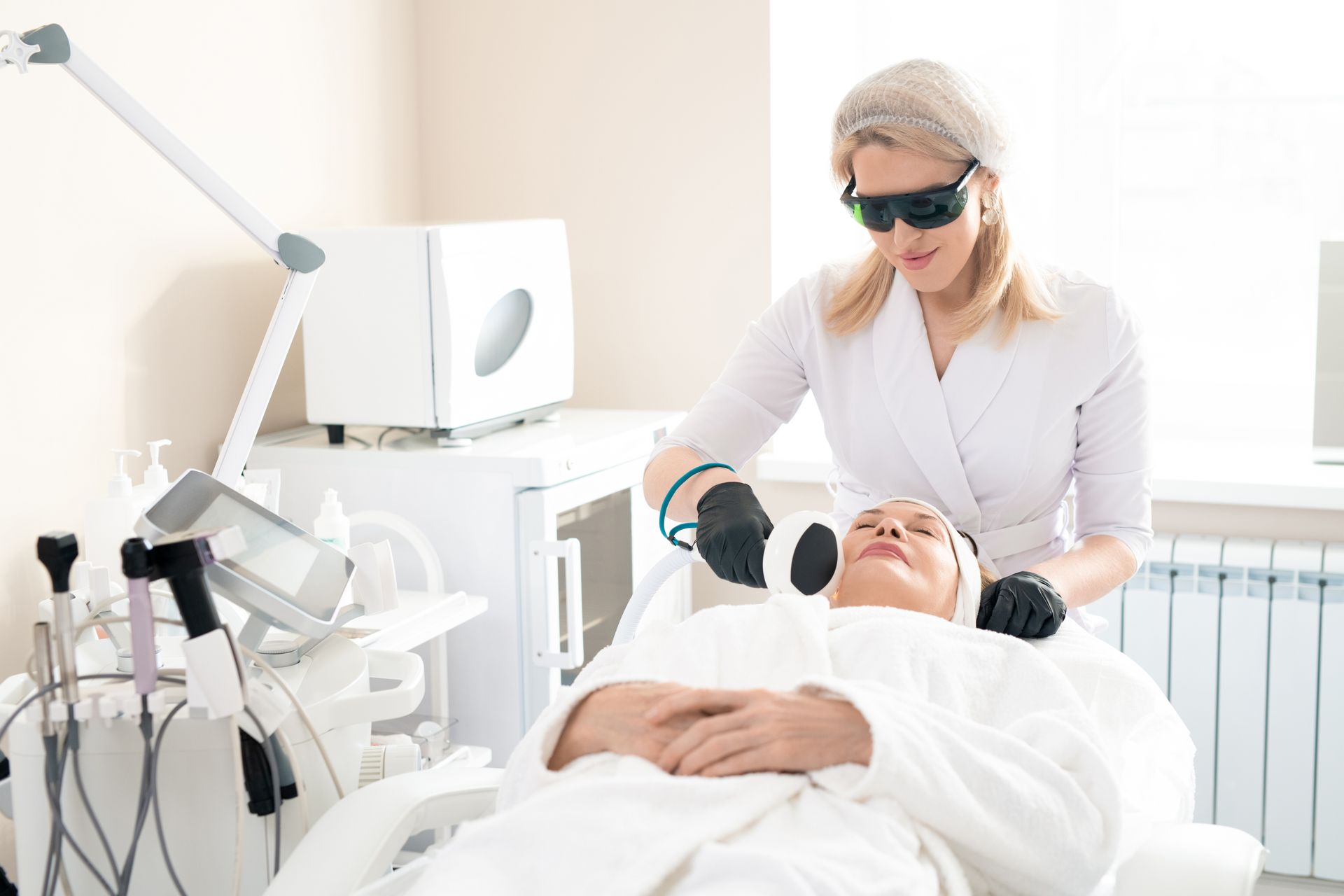 A woman is getting a laser treatment on her face in a beauty salon.