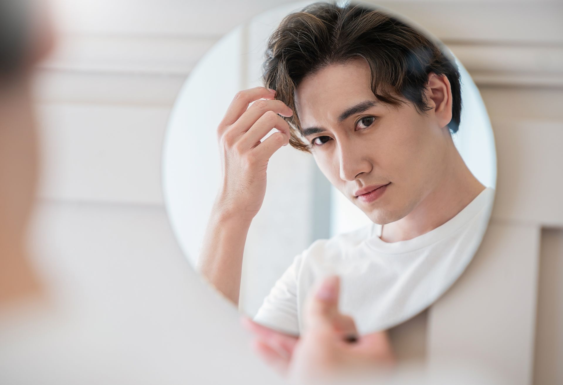 A young man is brushing his hair in front of a mirror.