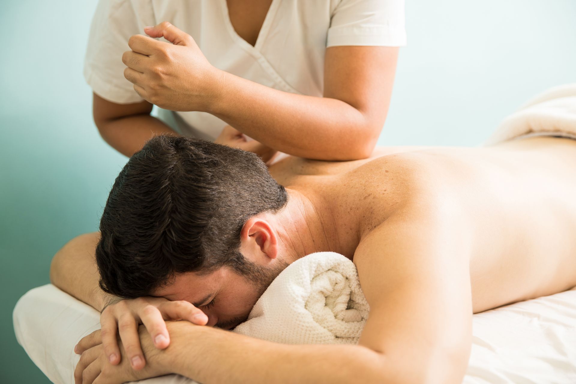 A man is laying on a table getting a massage from a woman.