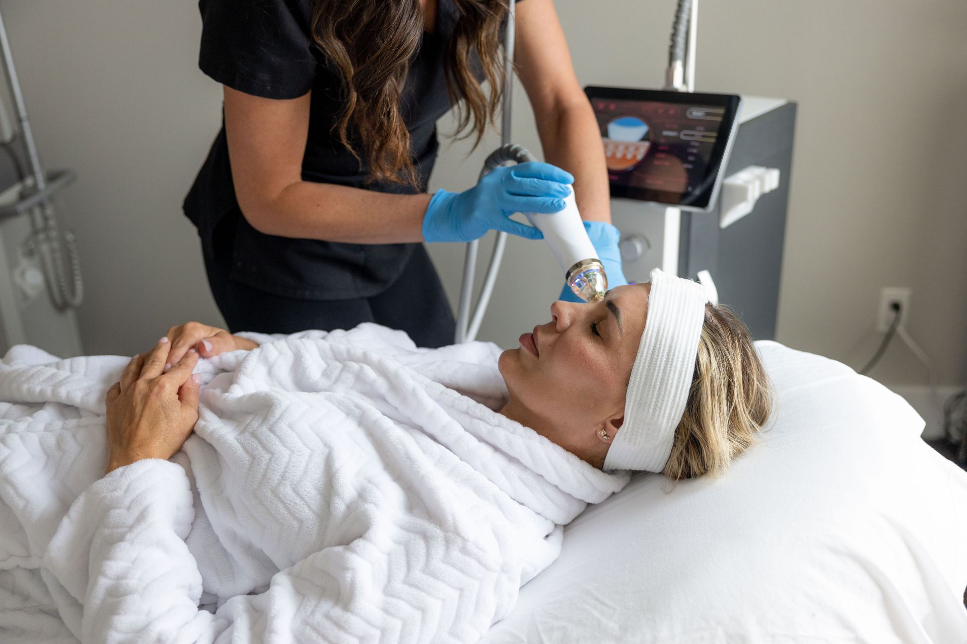 A woman is laying on a bed getting a facial treatment.