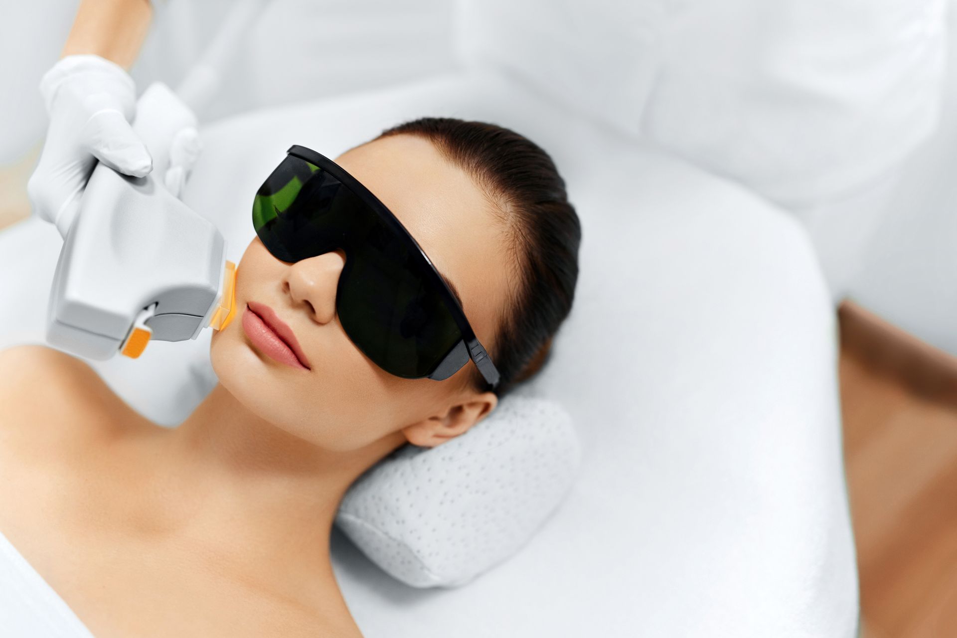 A woman is getting a laser hair removal treatment on her face.