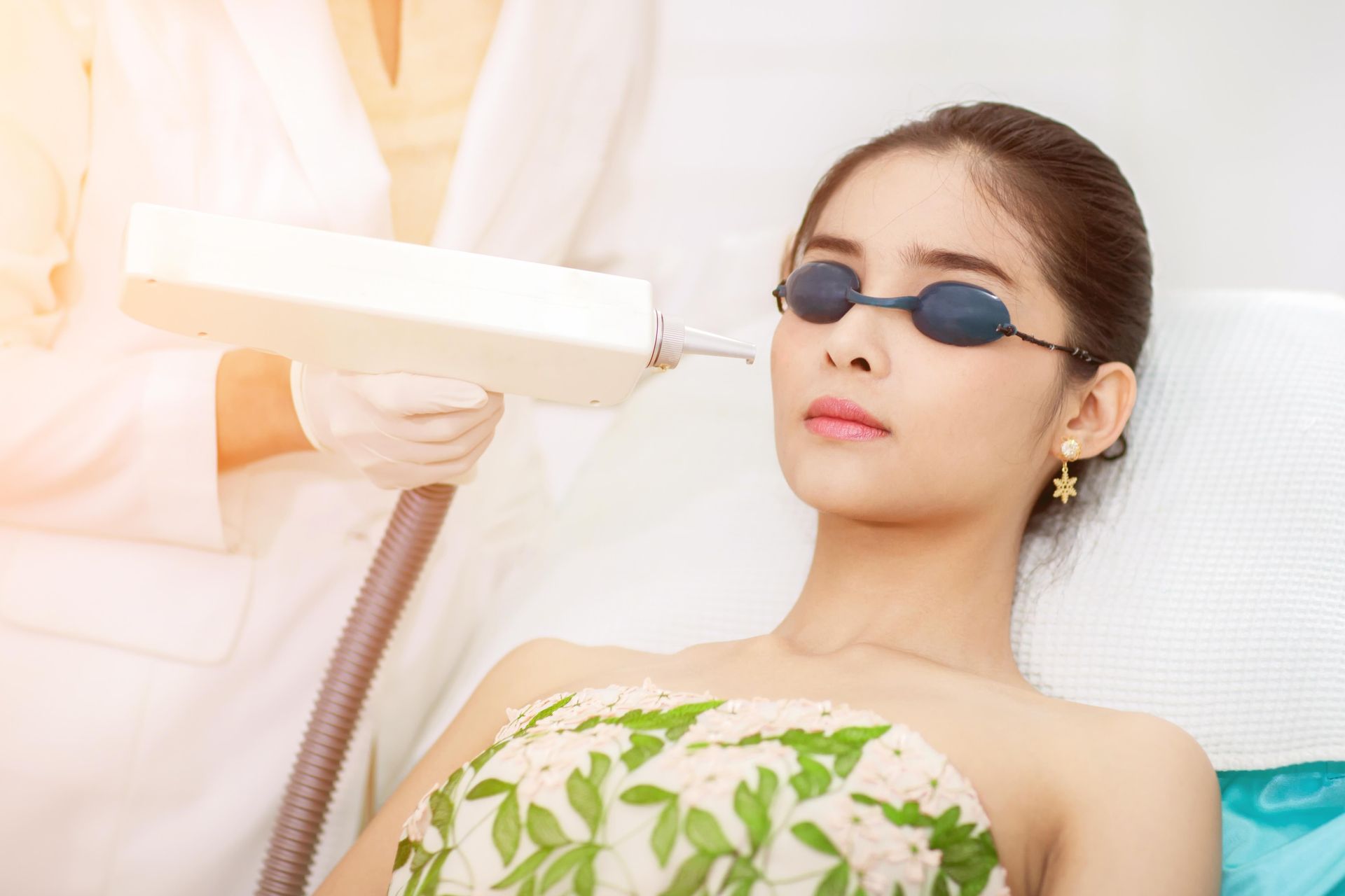 A woman is getting a laser hair removal treatment on her face.