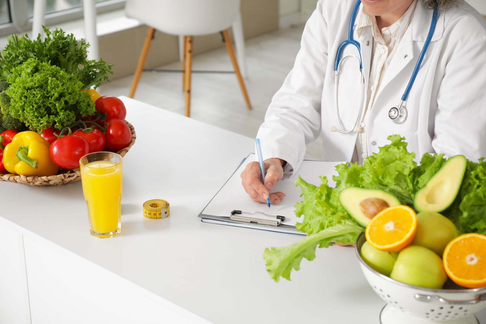 Doctor writing on clipboard beside fresh fruit and vegetables on a white table
