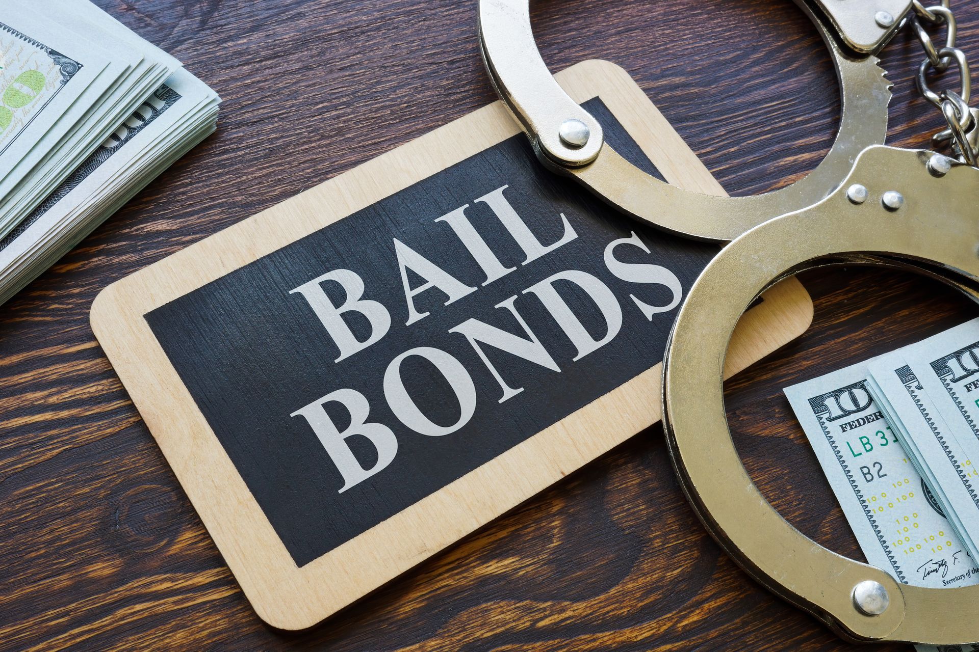 A sign that says `` bail bonds '' next to handcuffs and money on a wooden table.