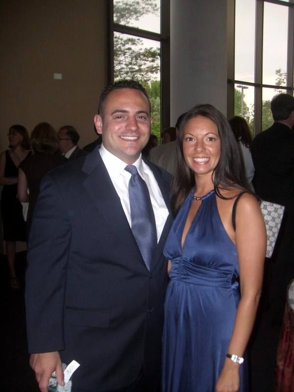 A man in a suit and tie stands next to a woman in a blue dress