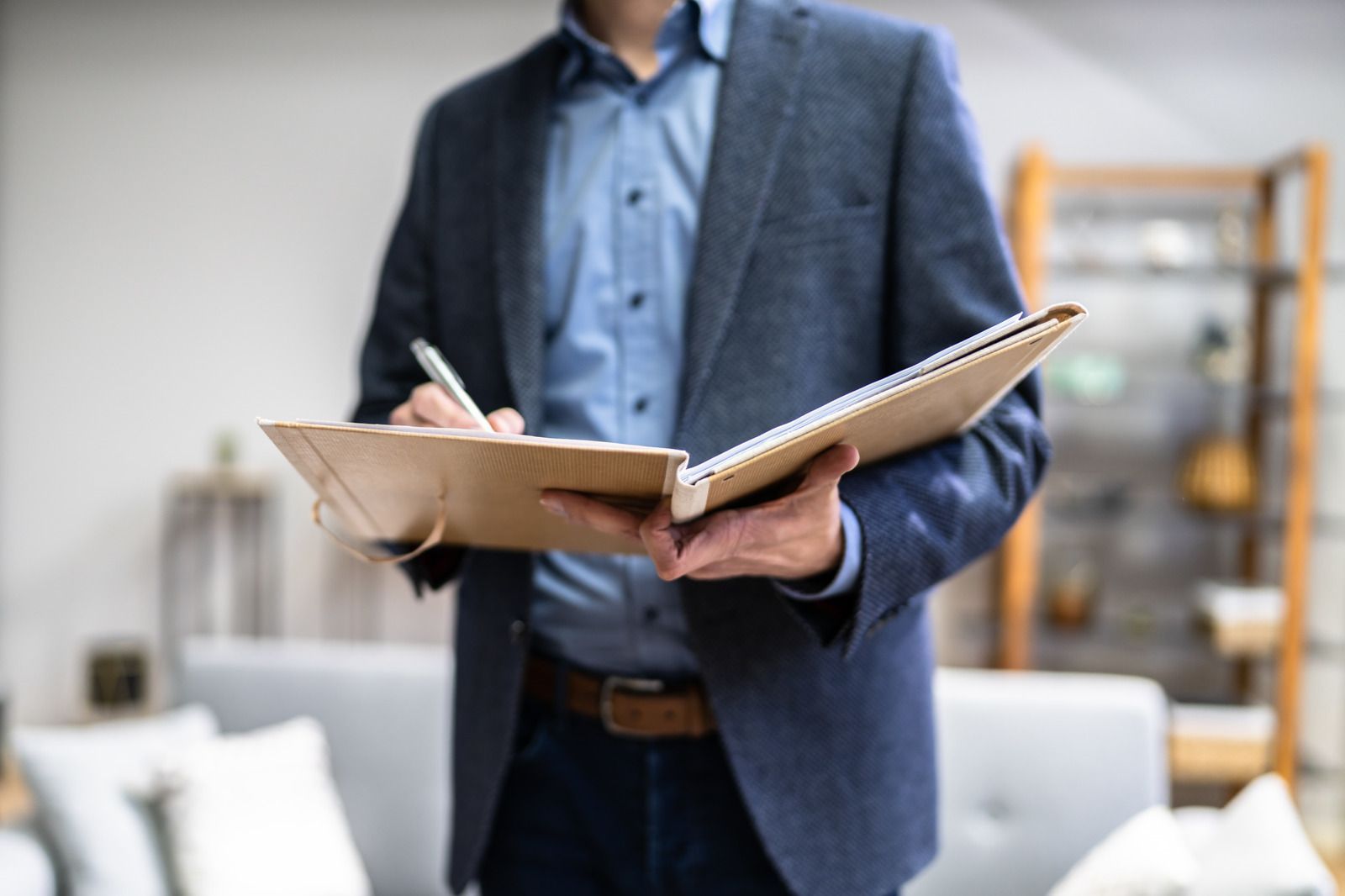 A man in a suit is holding a clipboard and writing in it.