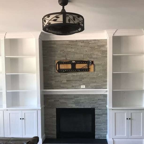 Built-in white bookshelves framing a fireplace with a stone accent wall, holding a TV mount.