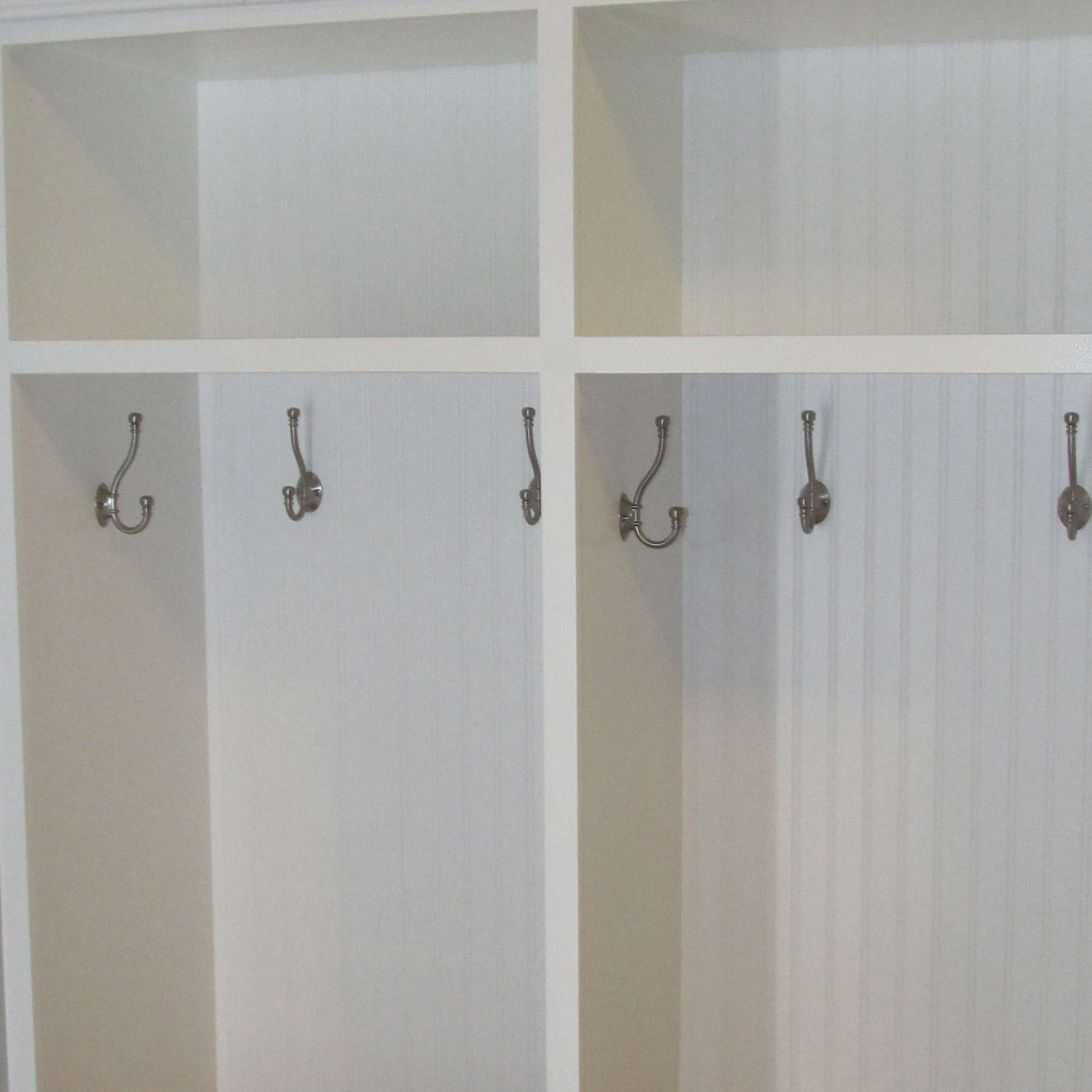 White storage unit with coat hooks.