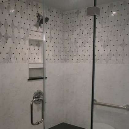 Shower stall with diamond-patterned tile, white walls, glass door, and chrome fixtures.