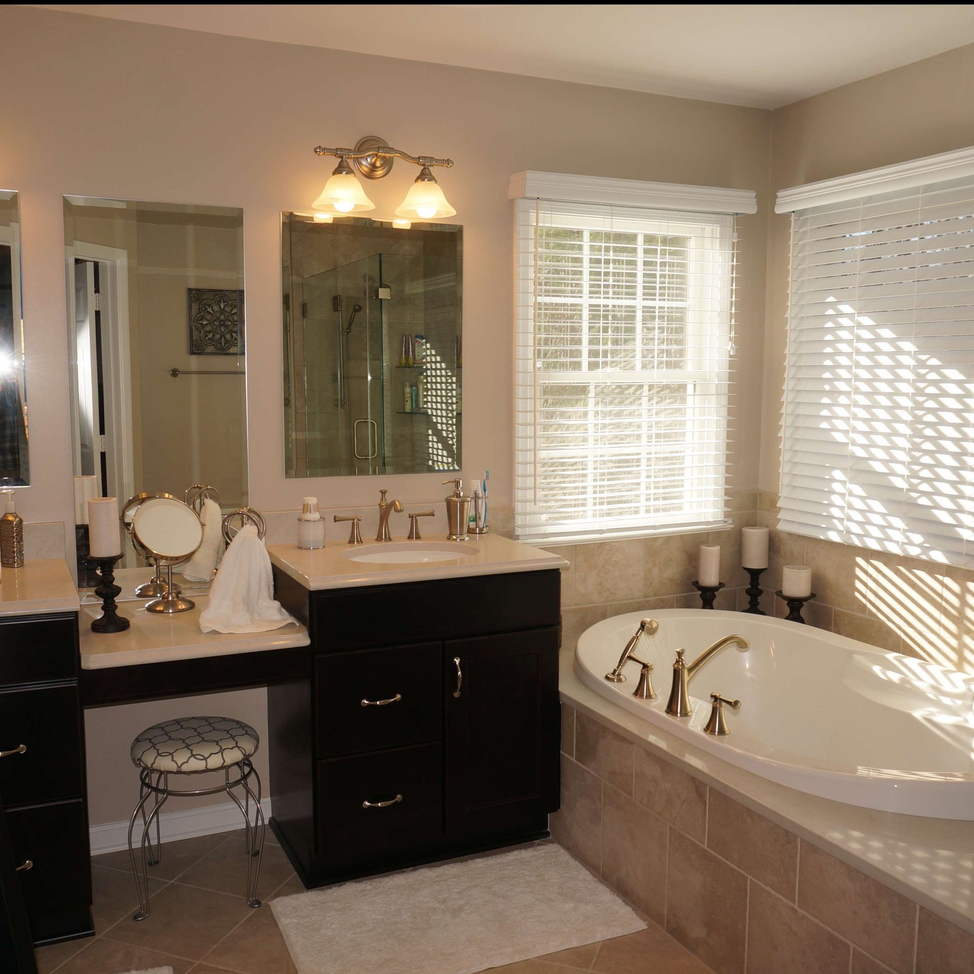 Bathroom with a vanity, bathtub, and window. Beige walls, dark cabinetry, and white accents.