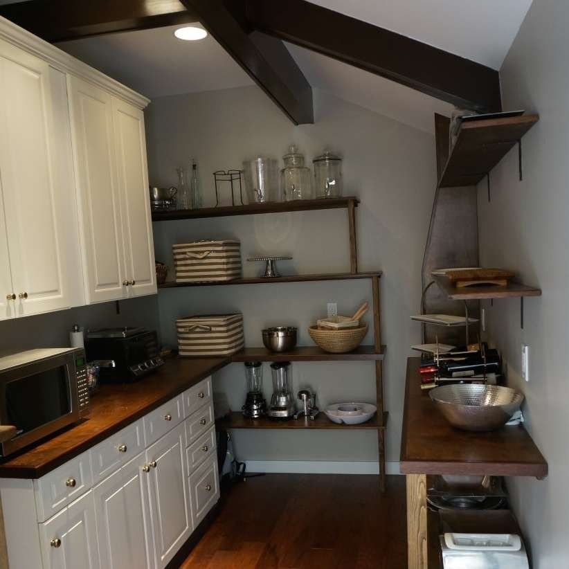 Kitchen with white cabinets, wooden countertops, open shelving, and wooden beams.
