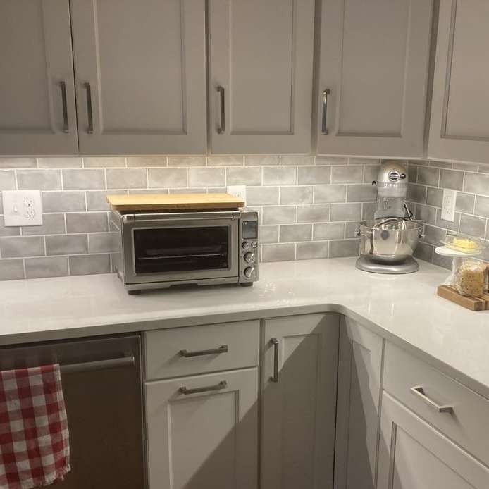 A kitchen corner with a countertop, cabinets, and appliances. An oven is centered, and a stand mixer is to the right.