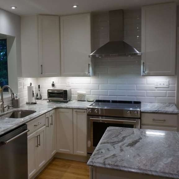 White kitchen with stainless steel appliances and gray countertops.