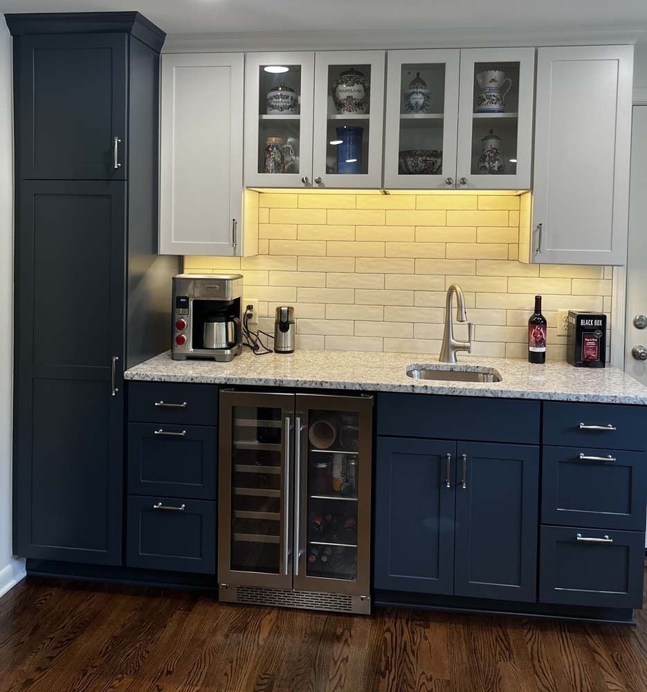 Kitchenette with blue and white cabinets, wine fridge, and coffee maker.