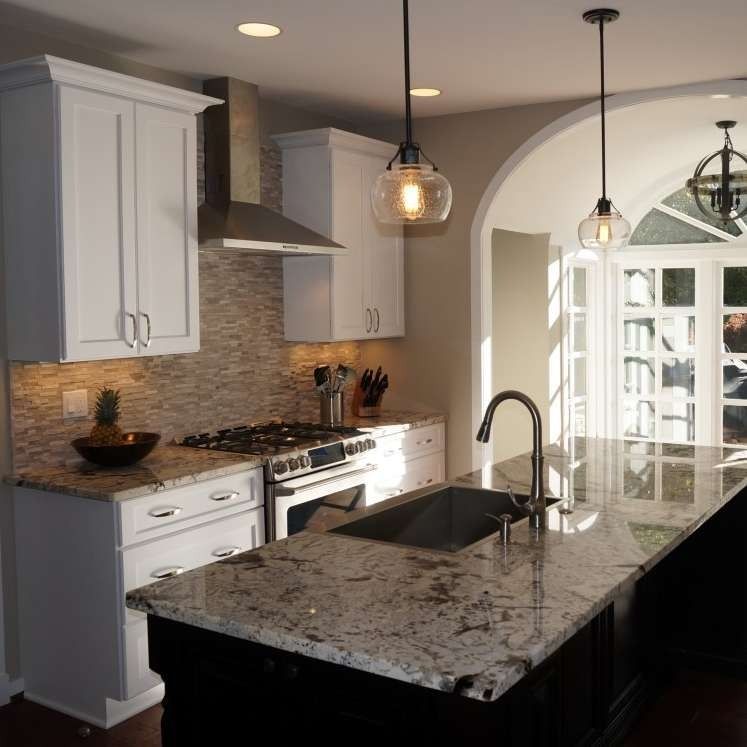 White kitchen with granite countertops, stainless steel appliances, and globe pendant lights.