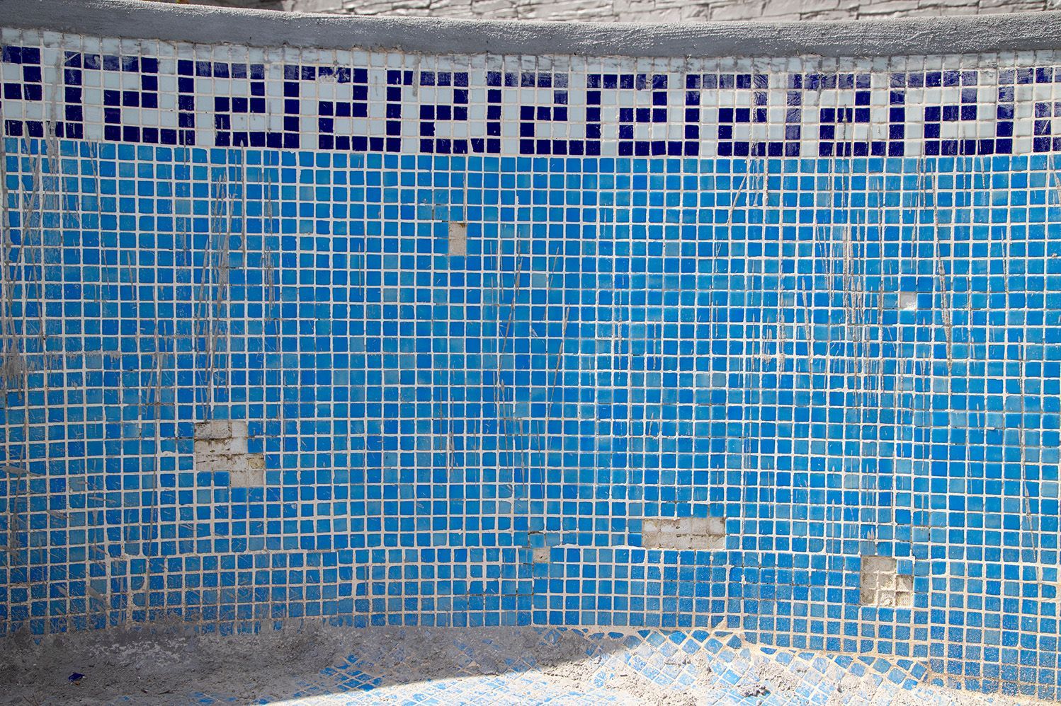 A blue tiled wall with a greek key pattern on it