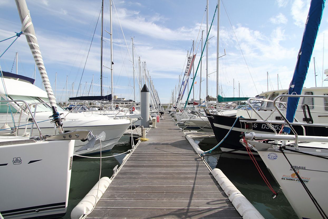 A row of boats are docked at a marina and one of them has a license plate that starts with the letter a