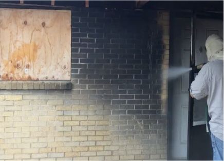 A person is cleaning a tile wall with a high pressure washer.