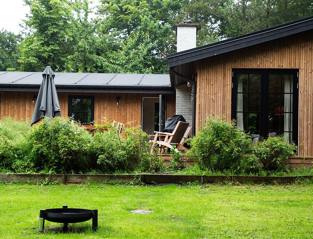 Træhus med have, havemøbler og grønne områder.