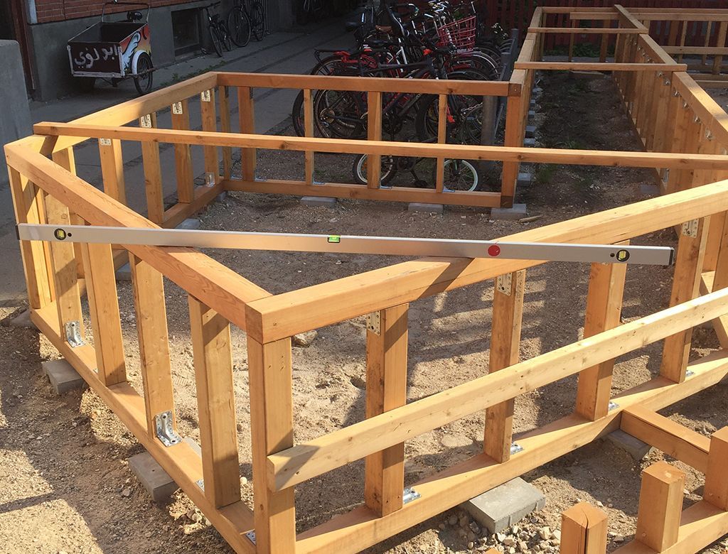 Trærammekonstruktion under opførelse, i vater på en vandret bjælke.