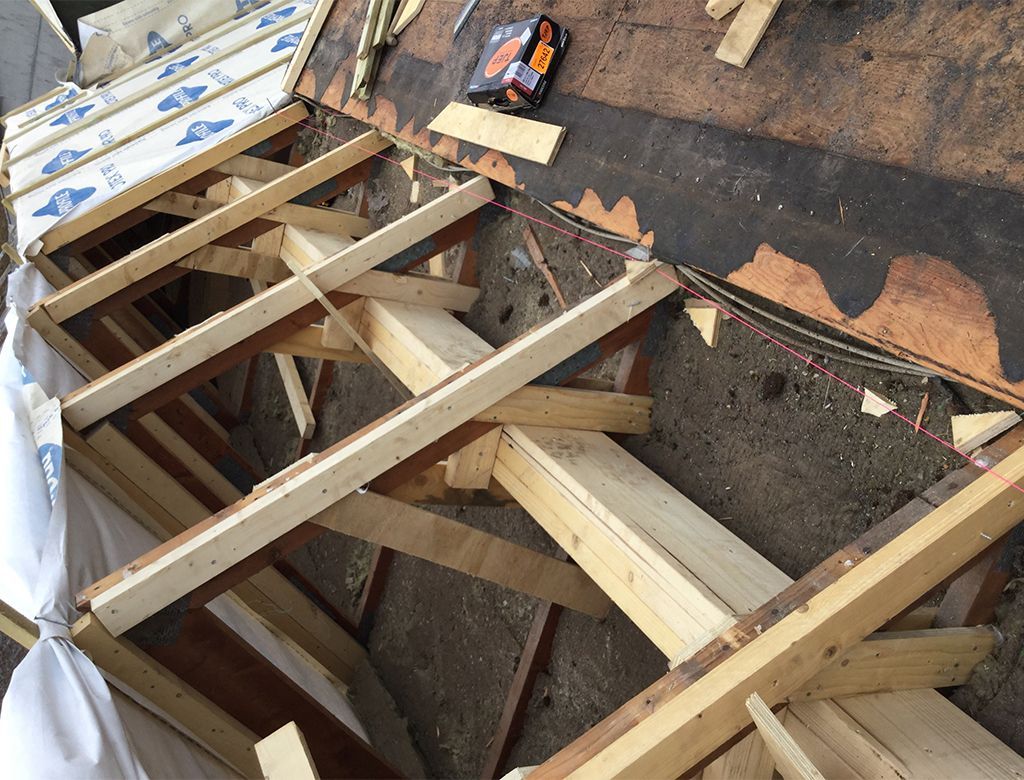 Tagspær af træ opføres på et tag, brædder og værktøj synlige.